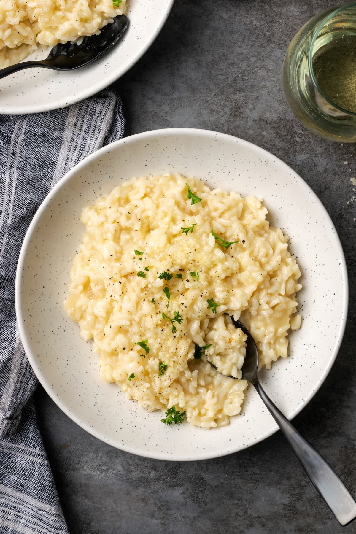 A bowl of creamy Instant Pot risotto with a spoon, garnished with fresh parsley.